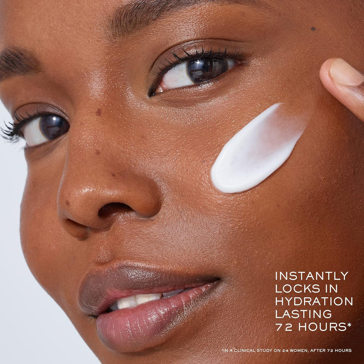 Model applying Lancome Genifique Night Repair Cream on cheek. The product locks in hydration and leaves skin glowing.