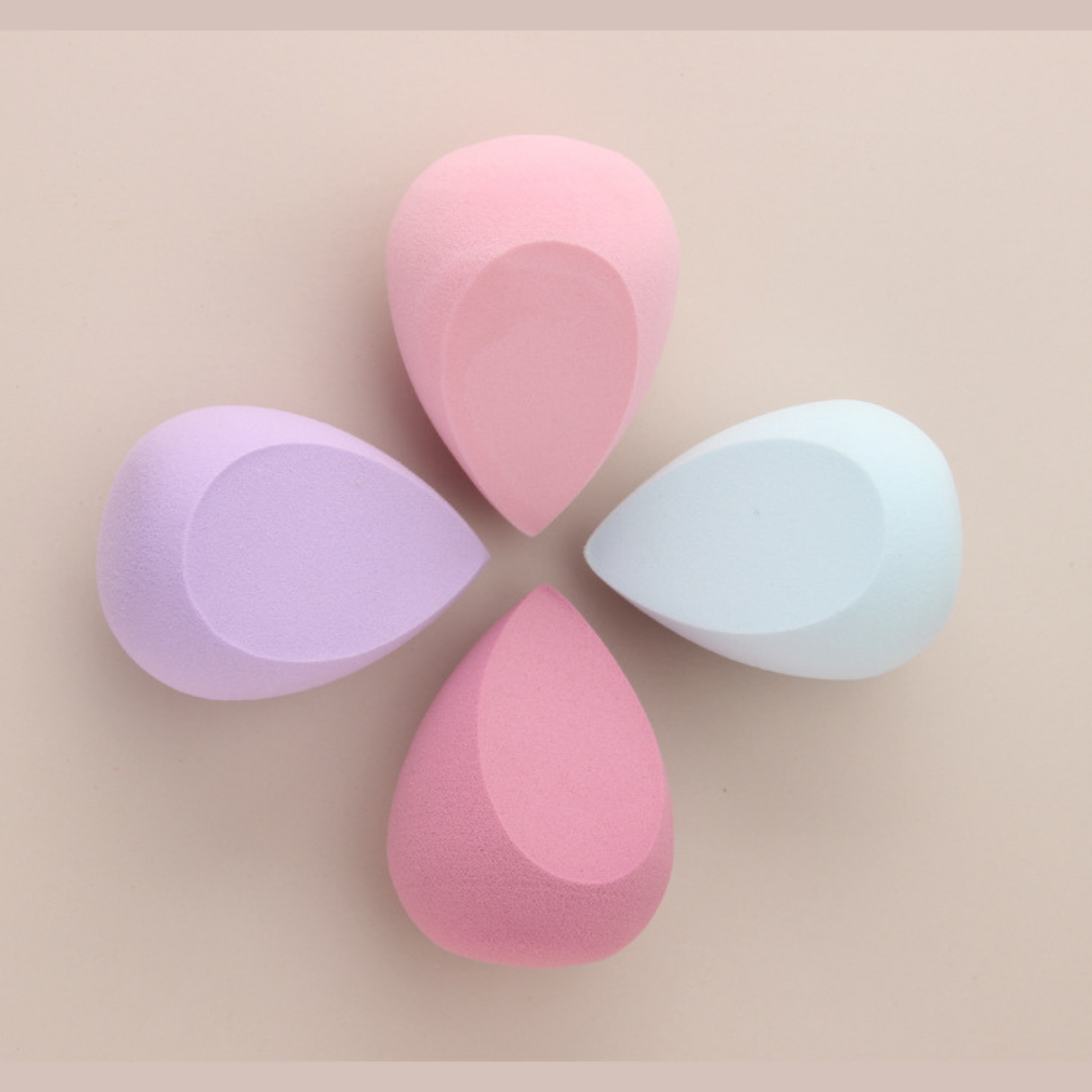 Four pastel makeup blending sponges arranged in circular pattern for versatile beauty use.