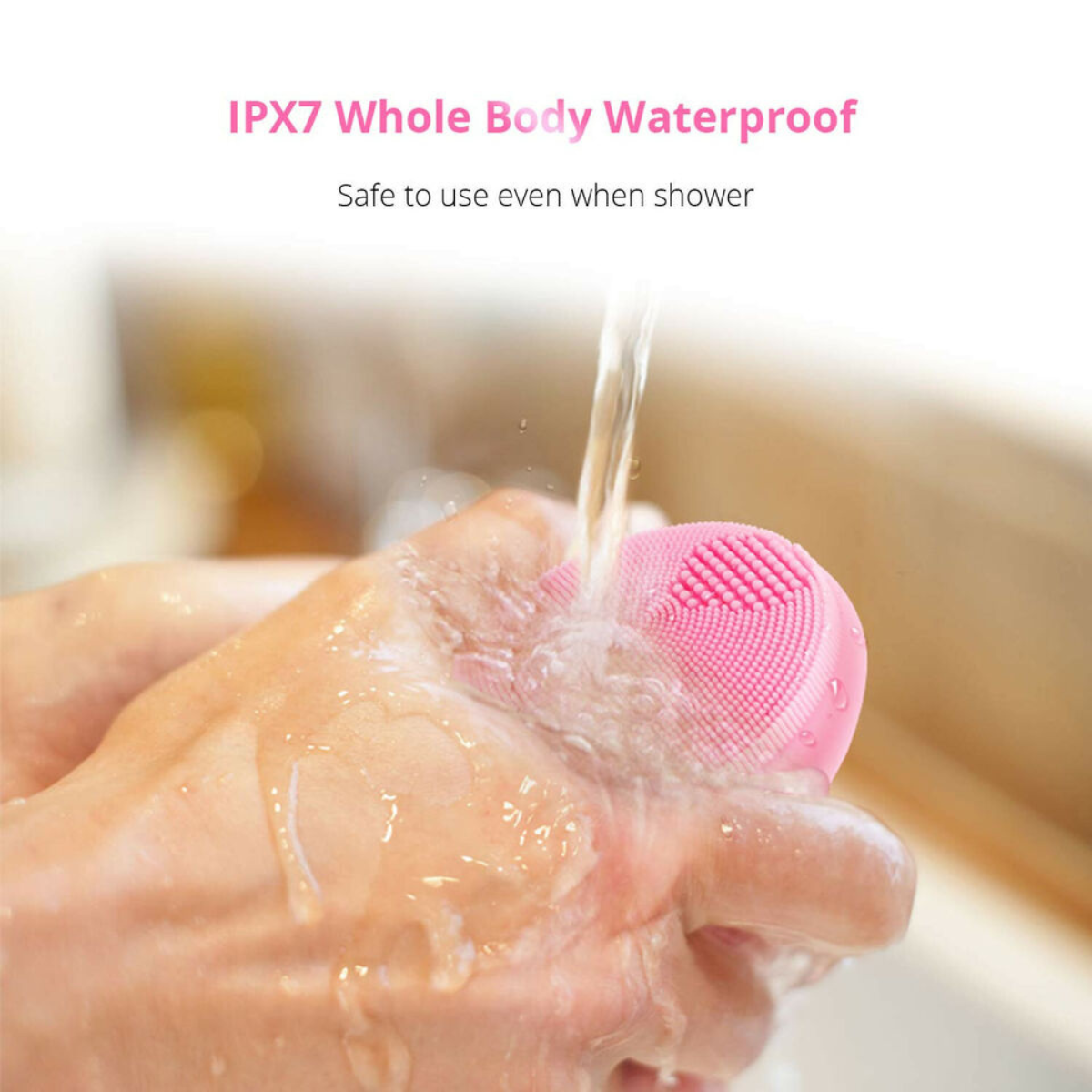 Wireless silicone facial cleansing brush being rinsed under running water. IPX7 waterproof design allows safe use in the shower.