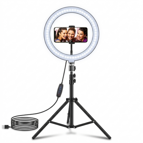 An adjustable 10-inch LED ring light with a cool white glow, mounted on a sturdy black tripod stand. Centered within the ring is a smartphone holder displaying a vibrant photo, while a power cable with an integrated remote is coiled at the base.