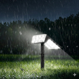 A durable solar landscape light shines brightly in a grassy yard during a nighttime rainstorm. The image demonstrates the product's waterproof capabilities, showing it functioning perfectly while exposed to heavy rain and outdoor elements.