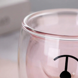 Close-up of the double wall glass cup rim and printed face detail. Smooth glass edge with a soft pink tint inside.