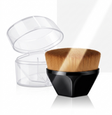 This black flat-top foundation brush with brown bristles stands alongside its open, transparent storage case. The image highlights how the brush can be stored or carried for hygiene.