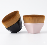 This image of a flat-top foundation brushes with synthetic bristles, one with a black handle and the other with a pink handle. The brushes are presented on a clean white surface with minimal shadows.