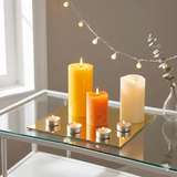 Frameless mirror tile set used as a decorative base with candles on a table. Reflective square tiles ideal for décor and display setups.