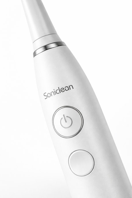 Sonic toothbrush handle close-up showing power button and sleek design