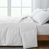 White duvet spread on bed with pillows in a bright bedroom setting.